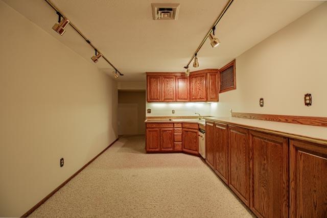 6 Cedar Lake Dr, Butte, MT 59701 - kitchen with track lighting, light carpet, light countertops, brown cabinets, and a sink