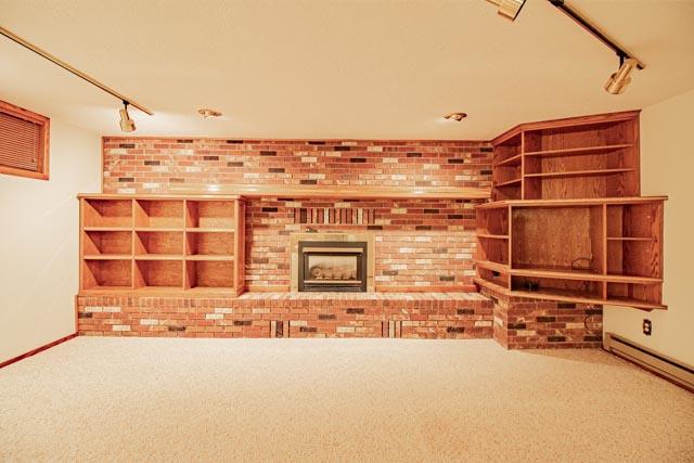 6 Cedar Lake Dr, Butte, MT 59701 - unfurnished living room featuring rail lighting, carpet, brick wall, and a baseboard radiator