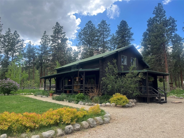 view of side of property with a chimney, covered porch, and a yard