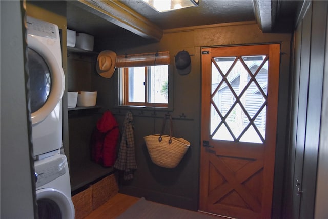 doorway with stacked washer / drying machine, plenty of natural light, and wood finished floors