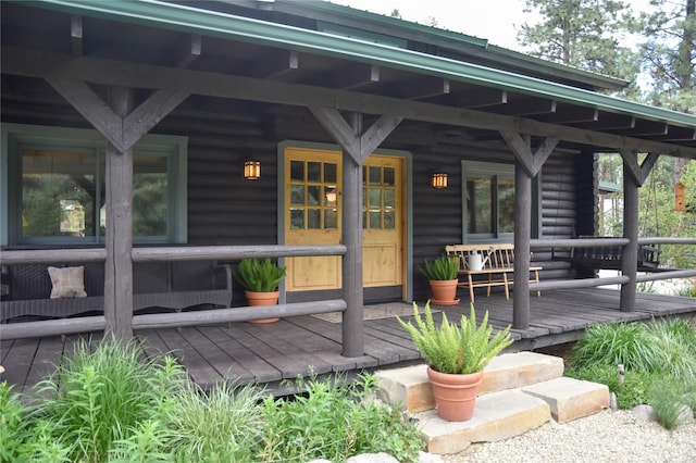 doorway to property featuring covered porch and log siding