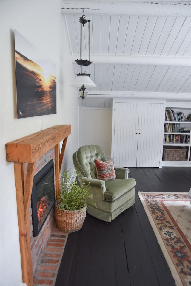 living area with wood-type flooring, beam ceiling, a glass covered fireplace, and wooden ceiling