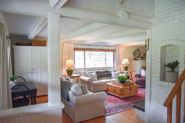 living area with light wood-style floors and beam ceiling