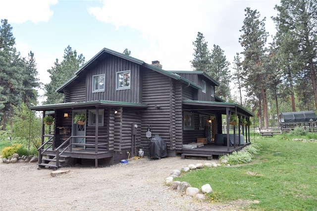 back of property with a porch, a chimney, and a yard