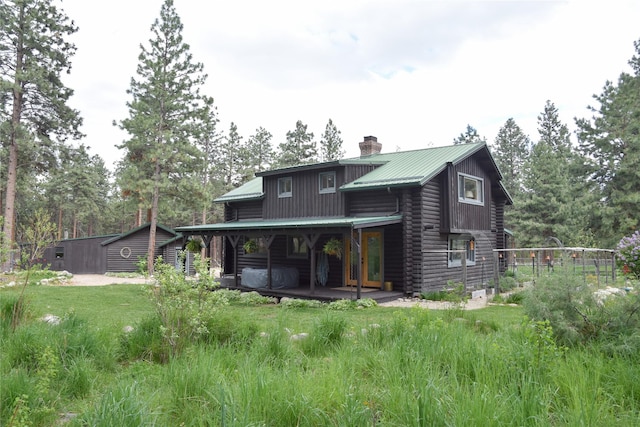 back of property featuring log exterior, a chimney, and metal roof