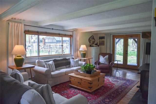 living area with healthy amount of natural light, hardwood / wood-style floors, beamed ceiling, and french doors