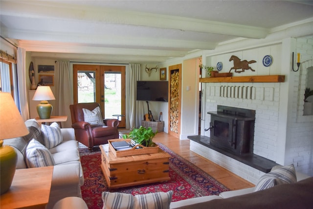 living room with wood finished floors, beamed ceiling, french doors, and a wood stove