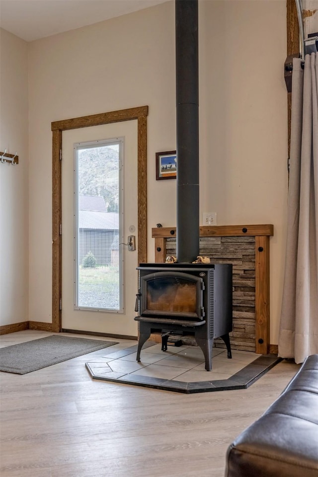 entryway with a wood stove, wood finished floors, and baseboards