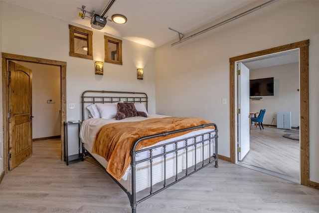 bedroom with light wood-style floors, a garage, and baseboards
