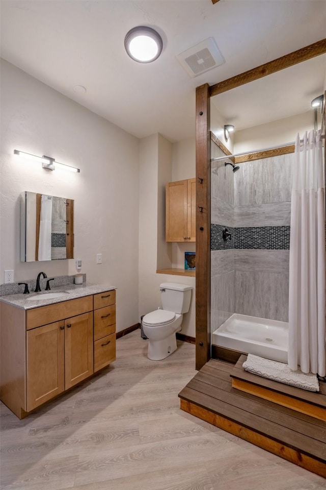 full bathroom with a shower with curtain, toilet, wood finished floors, baseboards, and vanity