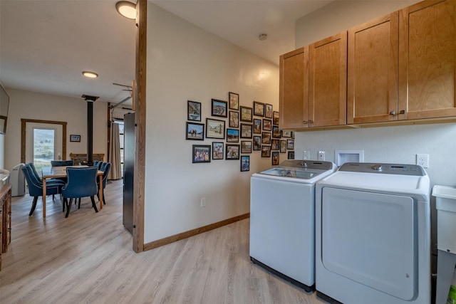 washroom with cabinet space, washer and dryer, light wood-type flooring, and baseboards