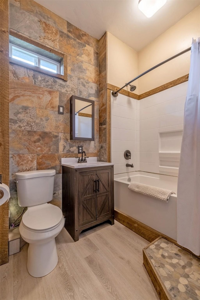 full bath featuring wood finished floors, toilet, vanity, shower / bath combination with curtain, and tile walls
