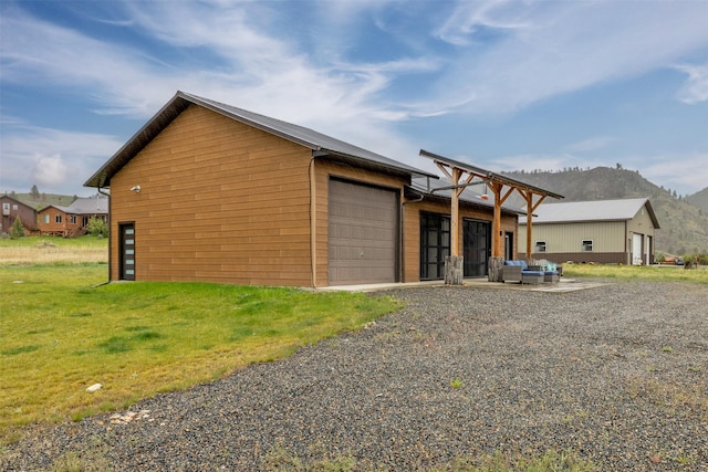 back of property featuring a mountain view, a yard, a garage, and an outbuilding