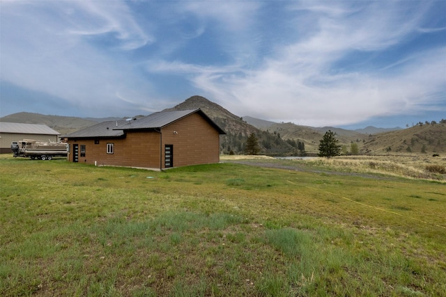 view of side of home with a mountain view and a lawn