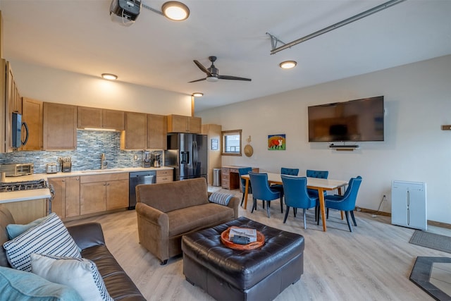 living room featuring light wood finished floors, ceiling fan, and baseboards