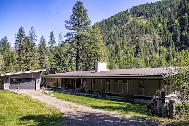 318 Mt Highway 56, Noxon, MT 59853 - farmhouse with a view of trees, a chimney, a front yard, a garage, and board and batten siding