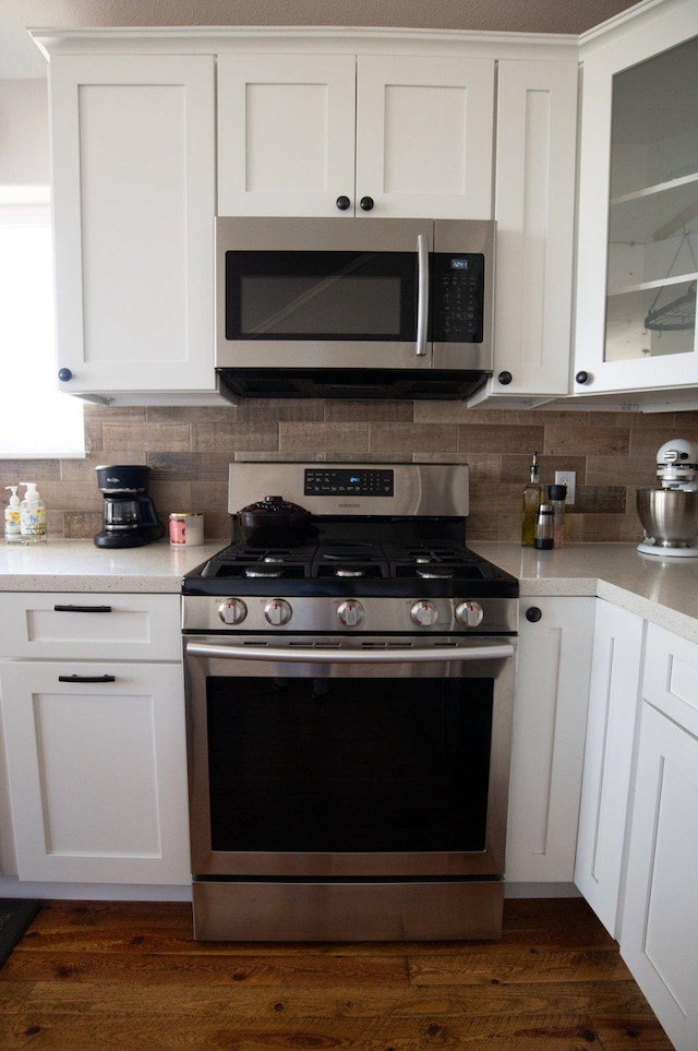 4714 Linhart Ln, Stevensville, MT 59870 - kitchen featuring appliances with stainless steel finishes, tasteful backsplash, white cabinets, light countertops, and dark wood-type flooring
