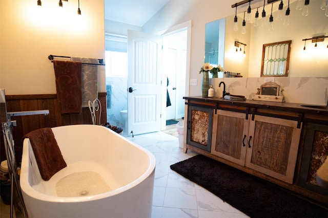 4714 Linhart Ln, Stevensville, MT 59870 - full bathroom featuring marble look tiles, a freestanding bath, vanity, wainscoting, and toilet