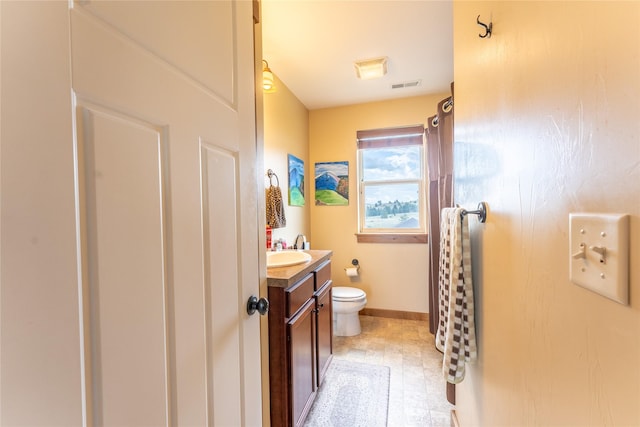 bathroom with toilet, vanity, and baseboards
