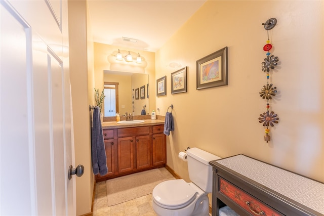 bathroom with toilet, vanity, and baseboards