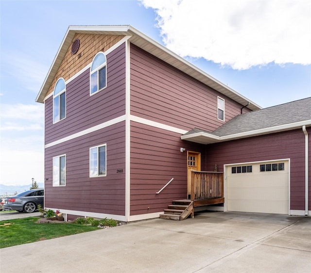view of side of property featuring an attached garage and driveway