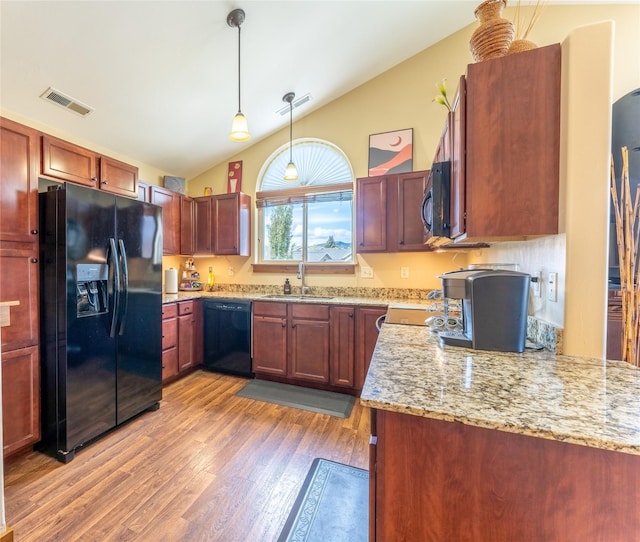 kitchen with black appliances, a sink, light wood finished floors, decorative light fixtures, and light stone counters
