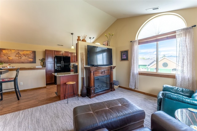 living room featuring lofted ceiling, baseboards, and light wood-style floors