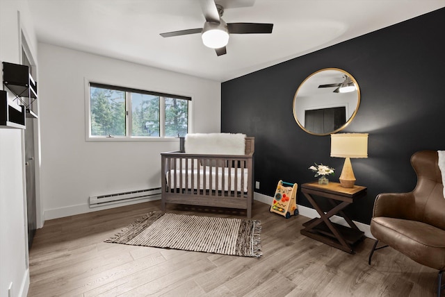 135 Sapphire Ct, Whitefish, MT 59937 - bedroom with baseboard heating, wood finished floors, baseboards, a nursery area, and ceiling fan