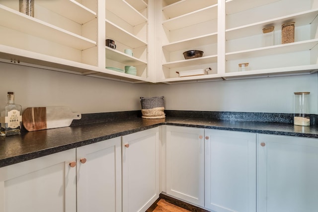kitchen featuring open shelves, dark countertops, white cabinets, and wood finished floors
