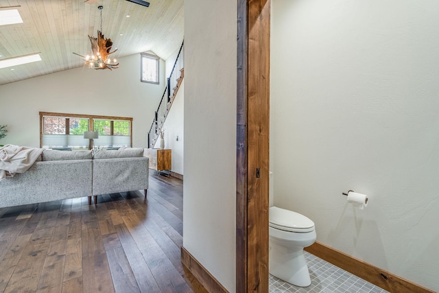 bathroom featuring toilet, a skylight, hardwood / wood-style flooring, a chandelier, and baseboards