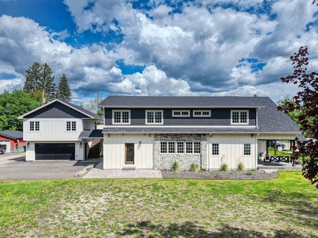 back of house featuring a yard, board and batten siding, a shingled roof, and stone siding