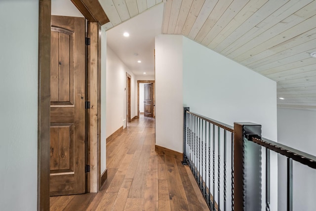 hallway with recessed lighting, wood-type flooring, an upstairs landing, wood ceiling, and baseboards