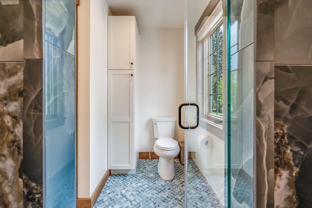 bathroom with baseboards, toilet, and an enclosed shower