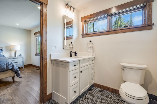 bathroom featuring baseboards, connected bathroom, toilet, wood finished floors, and vanity