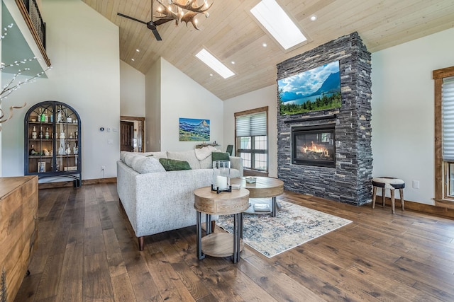 living area featuring a stone fireplace, high vaulted ceiling, wood-type flooring, a skylight, and wooden ceiling