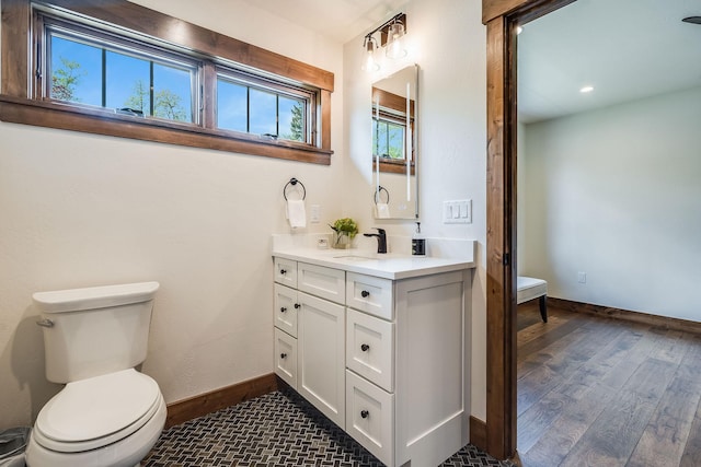 bathroom featuring baseboards, wood finished floors, toilet, and vanity