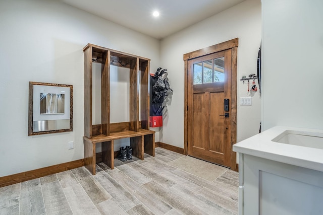 mudroom with light wood-type flooring, baseboards, and a sink