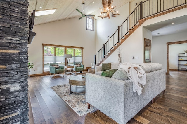 living room with high vaulted ceiling, healthy amount of natural light, a ceiling fan, dark wood-style floors, and stairs
