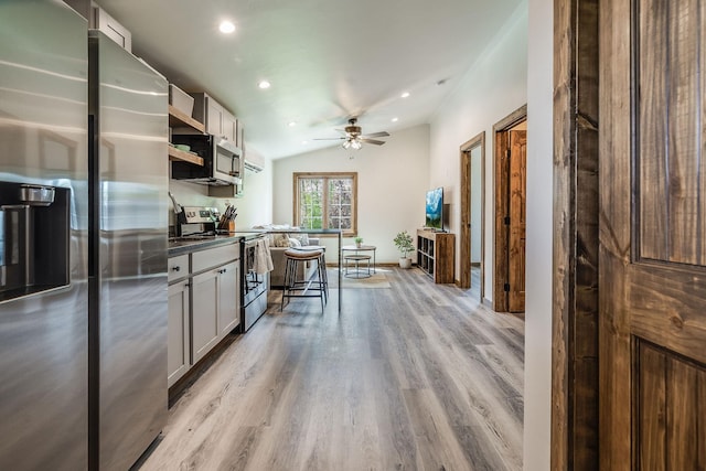 kitchen with stainless steel appliances, light wood finished floors, ceiling fan, recessed lighting, and dark countertops