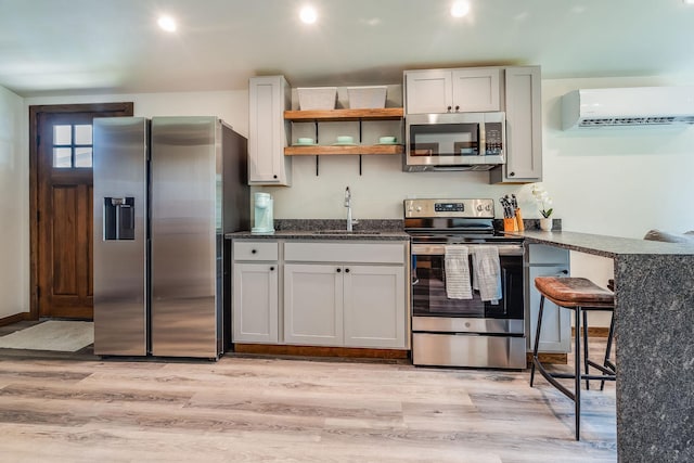 kitchen featuring appliances with stainless steel finishes, a sink, a wall mounted AC, light wood-style flooring, and recessed lighting