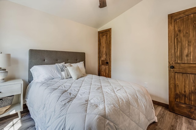 bedroom with vaulted ceiling, wood finished floors, baseboards, and ceiling fan