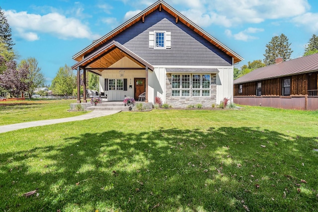 back of house featuring a porch, a lawn, and stone siding