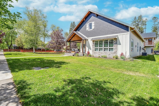 back of house with a lawn, stone siding, board and batten siding, and central AC unit