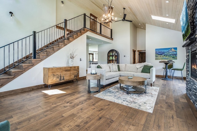 living area with high vaulted ceiling, stairway, a fireplace, hardwood / wood-style flooring, and baseboards