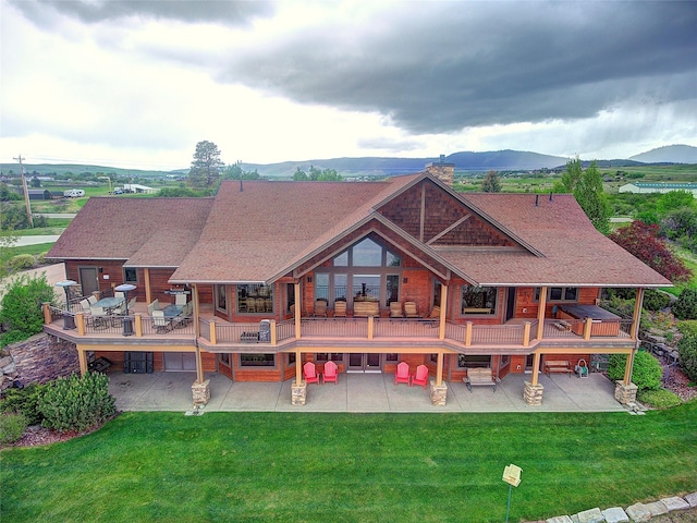 34520 Rocky Point Rd, Polson, MT 59860 - back of property featuring a patio, a deck with mountain view, a lawn, and a shingled roof