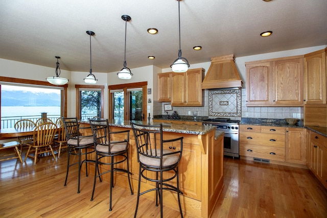 34520 Rocky Point Rd, Polson, MT 59860 - kitchen featuring premium range hood, high end stainless steel range, light wood finished floors, decorative backsplash, and a center island