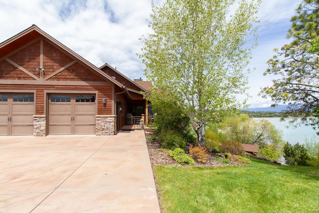 34520 Rocky Point Rd, Polson, MT 59860 - view of front of home with concrete driveway, stone siding, a garage, and a front yard