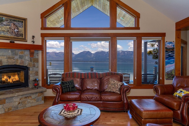 34520 Rocky Point Rd, Polson, MT 59860 - living area featuring healthy amount of natural light, wood finished floors, a stone fireplace, and high vaulted ceiling