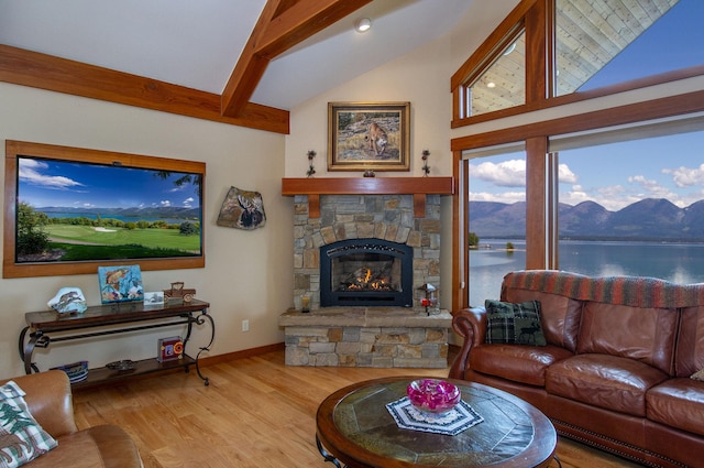 34520 Rocky Point Rd, Polson, MT 59860 - living room featuring wood finished floors, a stone fireplace, a water and mountain view, beam ceiling, and high vaulted ceiling