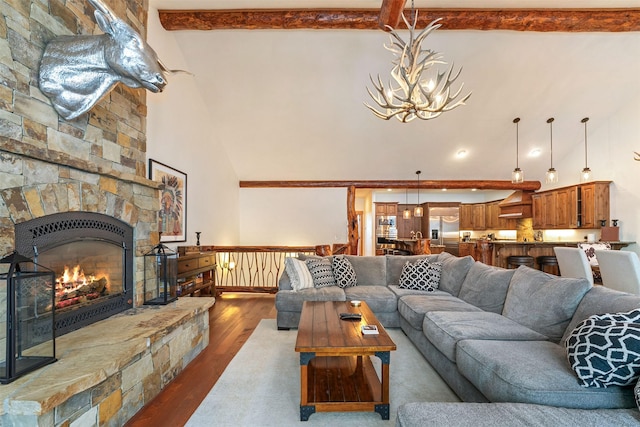 living room featuring high vaulted ceiling, a chandelier, wood finished floors, beam ceiling, and a fireplace